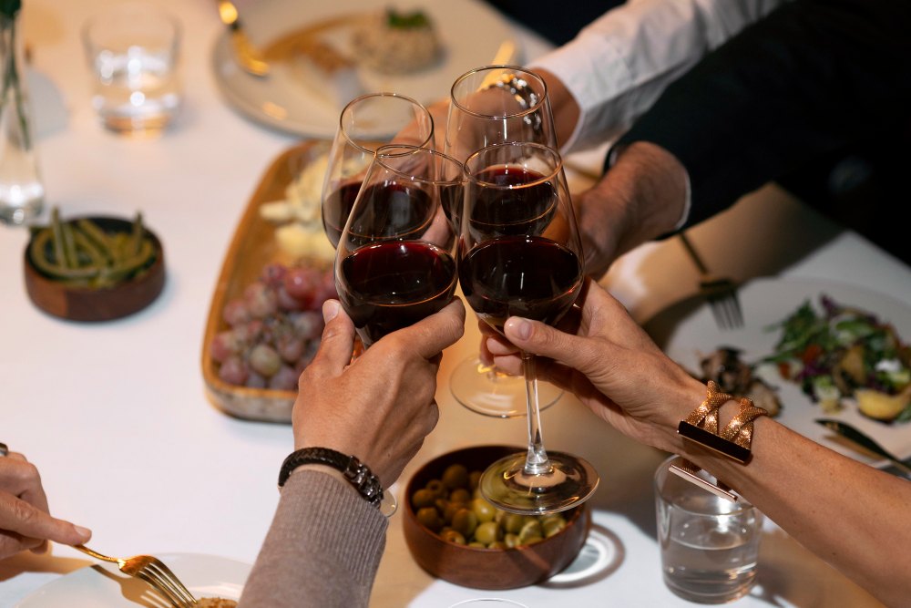Brindis con copas de vino tinto durante una celebración del Día del Padre con comida para compartir.